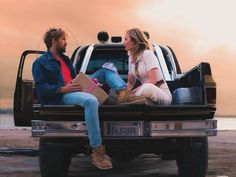 a man and woman sitting in the back of a pickup truck