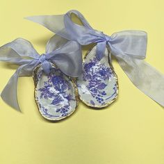 pair of blue and white porcelain shoes with ribbon on yellow background