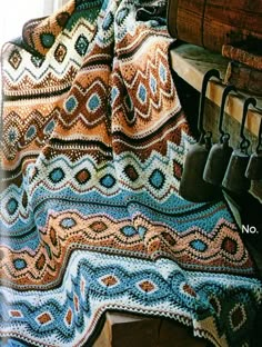 a crocheted blanket sitting on top of a wooden bench