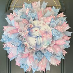 a pink and blue wreath with a snowman on it's front door,