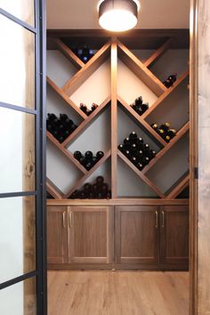 a wine rack in the corner of a room with wooden cabinets and doors leading to it