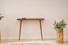 a wooden table sitting on top of a hard wood floor next to a potted plant