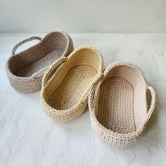 three crocheted baskets sitting on top of a white sheet covered floor next to each other