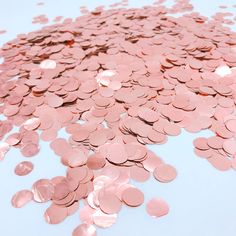 a pile of pink confetti sitting on top of a blue tablecloth covered in lots of coins