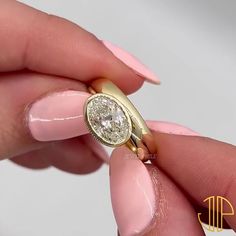 a woman's hand holding a ring with a diamond in the middle and a gold band around it