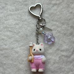 a keychain with a cat holding a piece of jewelry on it's side