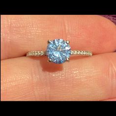 a woman's hand holding a blue diamond ring