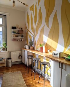 a kitchen with yellow and white wallpaper next to a window