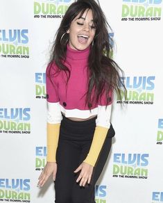 a woman with long hair wearing black pants and a pink sweater is posing for the camera