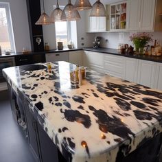 a kitchen with an island made out of cow hides and lights hanging from the ceiling