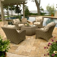 an outdoor living area with wicker furniture next to a swimming pool and gazebo