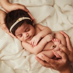 a woman holding a baby on top of a white blanket with her hands in the air