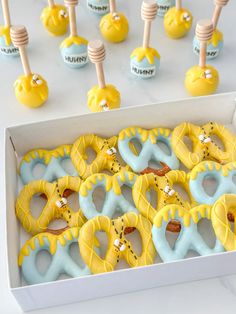 a box filled with yellow and blue donuts next to candy lollipops