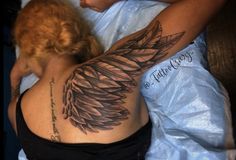 a woman laying in bed with a tattoo on her arm and back, showing the wings