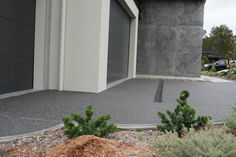 an empty parking lot in front of a building with plants growing out of the ground