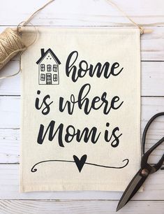 a sign that says home is where mom's are hanging on a white wall