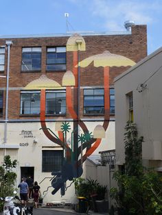 people are standing in front of a building with an artistic mural on it's side