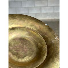 three large brass plates stacked on top of each other in front of a brick wall