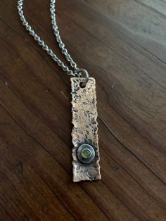 "This pendant is hand forged from thick, rustic bronze. It is accented with a reclaimed Sterling silver nugget and a small, 4mm natural peridot gemstone. Pendant comes with a 20\" closed link surgical stainless steel chain. This necklace is unisex in design and perfect for layering or wearing alone. Peridot is the traditional birthstone for those born in the month of August. MEASUREMENTS & SPECIFICS: PENDANT LENGTH: 5CM PENDANT WIDTH: 12MM NECKLACE LENGTH: 20\" NECKLACE MATERIAL: high qualit Bronze Stamped Pendant Jewelry, Rustic Bronze Electroformed Jewelry, Artisan Metal Jewelry With Stamped Details, Artisan Stamped Metal Jewelry, Unique Stamped Bronze Jewelry, Rustic Oxidized Finish Pendant Jewelry, Artisan Stamped Brass Jewelry, Nature-inspired Hammered Pendant Necklace, Rustic Bronze Soldered Necklace