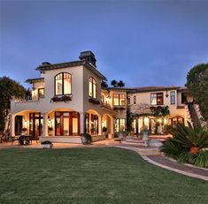 a large house with lots of windows and lights on it's front lawn area