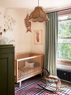 a baby's room with a rocking horse in front of the crib and window