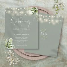 two wedding cards with string lights and flowers on the front, one is grey and the other is white