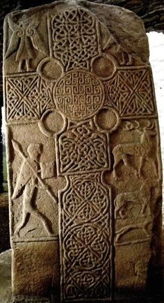 an intricately carved stone block in the shape of a cross, with symbols and figures on it