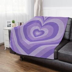 a purple and white heart shaped blanket on a couch in a room with hardwood floors