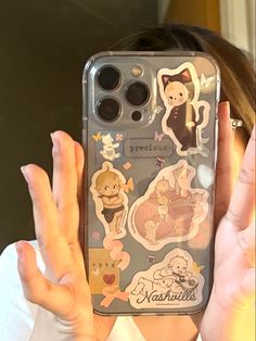 a woman holding up her phone case with stickers on it