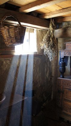 sunlight shining through the window into a room with wooden furniture and baskets hanging from the ceiling