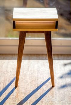 a small wooden table sitting in front of a window