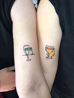 two people with matching tattoos on their arms holding wineglasses and champagne glasses in each hand