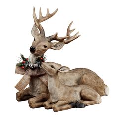 two deer statues sitting next to each other on top of a white background with red berries and pine cones