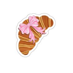 a sticker with a pink bow on it's head and some croissants in the background