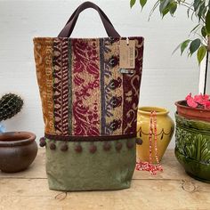 a handbag sitting on top of a wooden table next to potted plants and pots