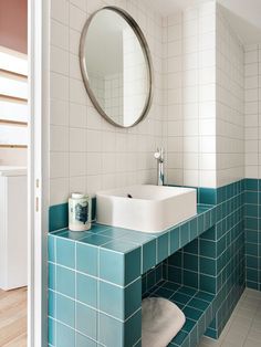 a bathroom with blue tiles and a round mirror