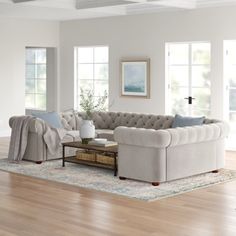 a living room filled with furniture on top of a hard wood floor covered in lots of windows