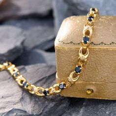 a close up of a gold chain with blue stones on it and a box in the background