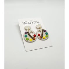 a pair of earrings with multicolored buttons on them sitting on top of a card