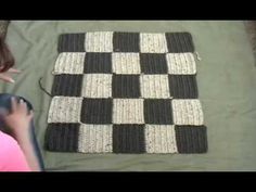 a woman sitting on top of a bed next to a black and white checkered rug