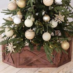 a small christmas tree in a wooden box with white and gold ornaments on the top