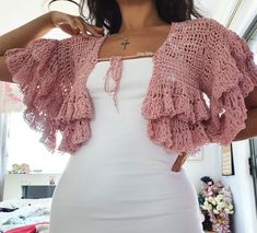 a woman wearing a pink crochet cardigan and white dress