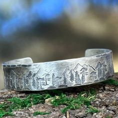 A rustic handmade bracelet that celebrates the beauty of nature and the majesty of the forest with the mountains and trees hand stamped around the rustic sterling silver cuff.  This bracelet is 12mm wide (1/2 inch) and 2mm thick.  Perfect for the hunter or hiker in your life.  This engraved silver bracelet is hand forged and finished with a hammered finish to give it a rustic look, perfect for men and women alike.  Each bracelet is handmade, and no two will be exactly alike. Also please be aware that colors may vary due to viewing screens. If you have any questions or want to create a custom piece, send me a message and we can talk about it! I look forward to doing business with you. How to determine your size:  Using the directions in the photos, choose the most appropriate size.  6 inch Mountains And Trees, Silver Engraved Bracelet, Ormond Beach, Black Sharpie, Personalized Bracelet, The Hunter, Sterling Silver Cuff Bracelet, Copper Bracelet, Personalized Bracelets