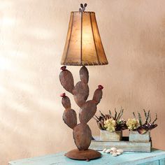 a lamp that is sitting on top of a table next to a small cactus plant