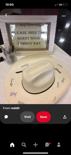 a white cowboy hat sitting on top of a table next to a sign that says please sign