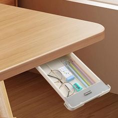 an open drawer underneath a table with glasses and pencils