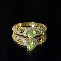 two yellow gold rings with green and white diamonds on black background, close up view