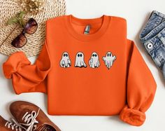 Halloween Embroidered Sweatshirt-Halloween Sweatshirt-Halloween Unique-Ghost-Halloween Shirt-Fall Sweatshirt-Custom Halloween Embroidered Sweatshirt-Spooky Season-Halloween Crewneck This custom made to order embroidered sweatshirt is super soft, unisex in size and makes a trendy sweatshirt to wear as the spooky season approaches. Embroidered Ghosts design on center chest measures approximately 7" in width by 3" in height. Design will be embroidered in black and white thread as shown on main desi Long Sleeve Custom Embroidered Sweatshirt For Halloween, Halloween White Embroidered Sweatshirt, Halloween Embroidered Crew Neck Hoodie, Halloween Embroidered Cotton Sweatshirt, Casual Long Sleeve Halloween T-shirt, Casual Embroidered Halloween T-shirt, Spooky Long Sleeve Orange T-shirt, Spooky Orange Long Sleeve T-shirt, Orange Sweatshirt