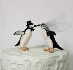 two penguins are kissing on top of a cake