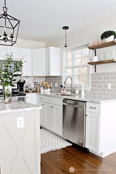 a kitchen with white cabinets and stainless steel dishwasher in the center, wood floors